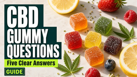 Colorful translucent hemp gummies are arranged with fresh fruit and small hemp leaves on a bright kitchen surface.