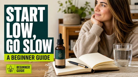 A labeled hemp oil bottle, notebook, pen, and glass of water sit together on a wooden table in a softly lit home.